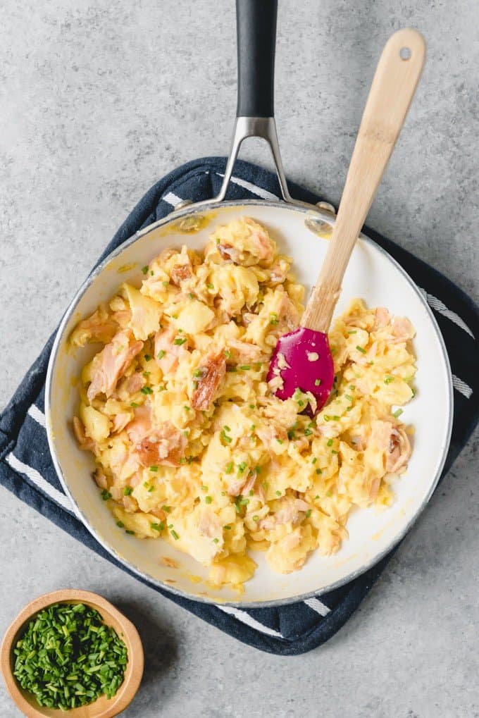 An image of a pan of smoked salmon scrambled eggs, sprinkled with fresh chopped chives.
