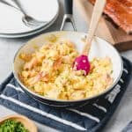 smoked salmon scrambled eggs in a skillet with a bowl of chives and smoke salmon fillet to the sides