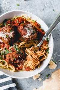 a white bowl with spaghetti and meatballs with a fork twirled in noodles