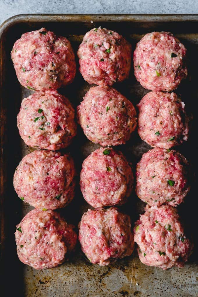 An image of twelve meatballs on a pan, ready to be cooked for classic spaghetti and meatballs.
