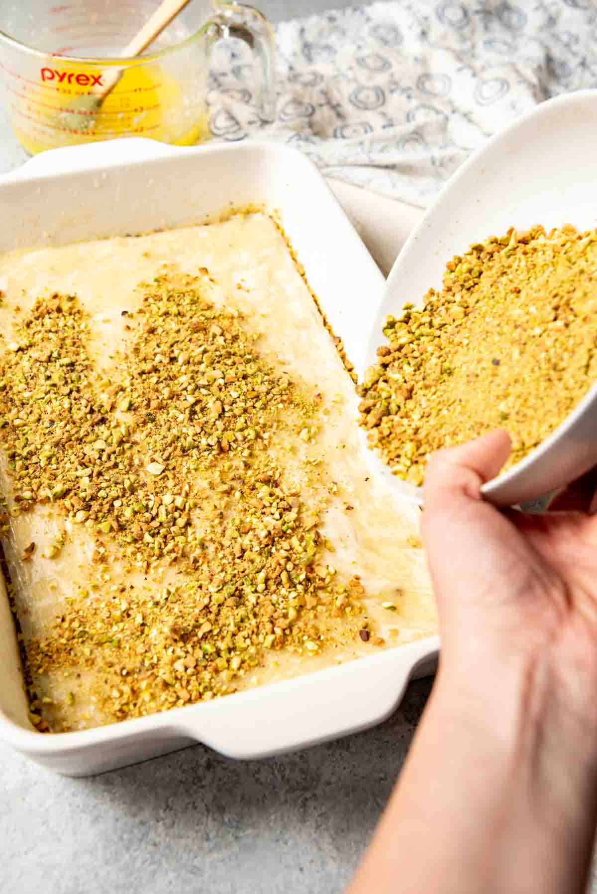 Sprinkling finely chopped pistachios over phyllo dough.