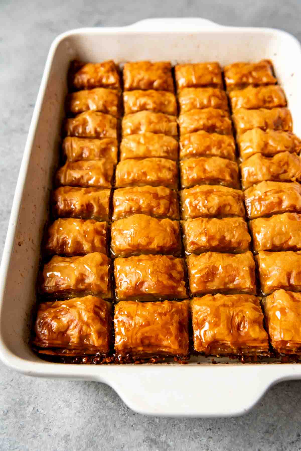 Baked baklava in a pan soaking in syrup.