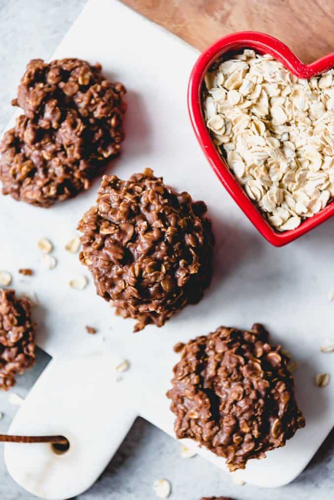 An image of chocolate no bake cookies next to a heart-shaped bowl of quick oats.