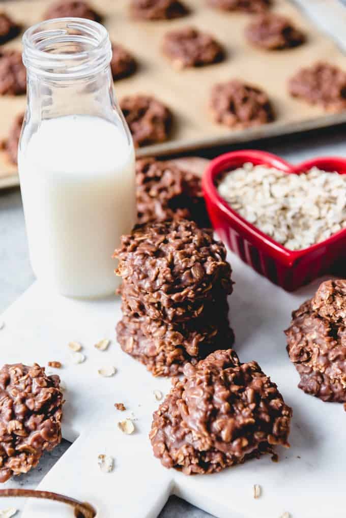 An image of chocolate peanut butter no bake cookies stacked on top of each other next to a jar of cold milk.
