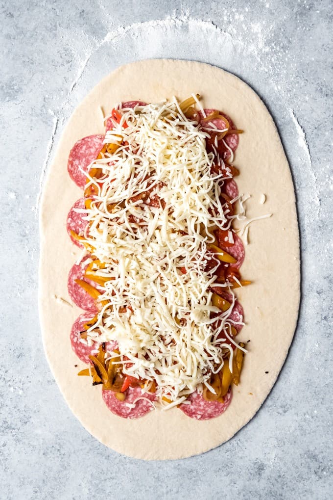 thin rolled dough topped with sausage, cooked peppers and onions and cheese