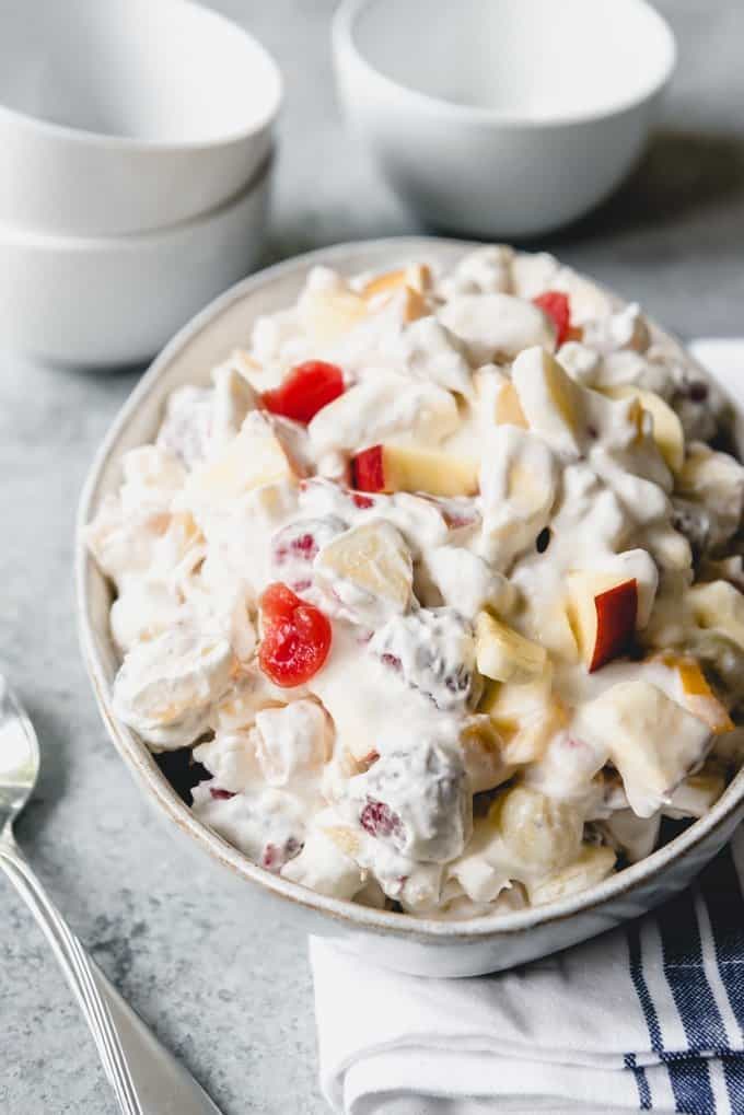 An image of a bowl of classic fruit salad or ambrosia with fruit cocktail, cherries, and marshmallows.