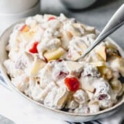 a bowl filled with fruit salad with marshmallows and whipped cream