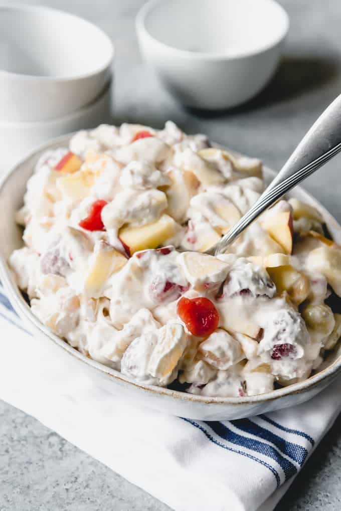 a bowl filled with fruit salad with marshmallows and whipped cream