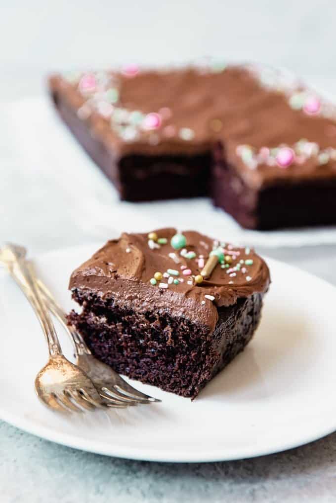 An image of a slice of an easy homemade chocolate cake recipe with homemade chocolate frosting and sprinkles on top.