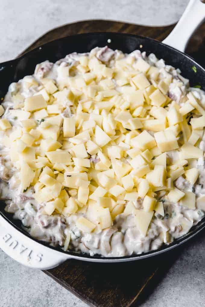 An image of an easy, cheesy dip topped with provolone cheese before being baked in the oven.