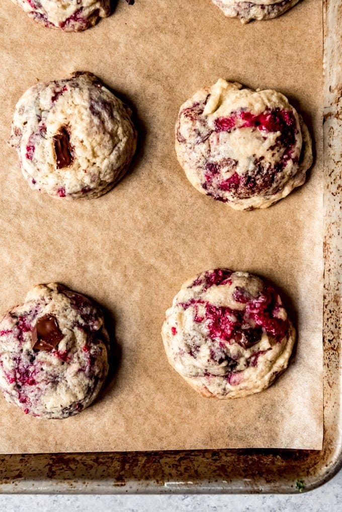 Soft and chewy raspberry chocolate chunk cookies on a piece of parchment paper.