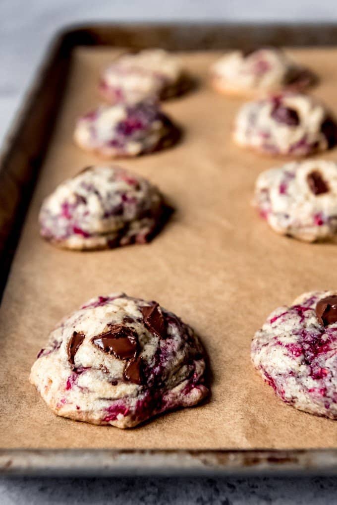 Chocolate chip raspberry cookies on a baking sheet lined with parchment paper.