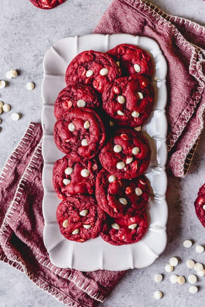 a plate of red velvet cookies with white chocolate chips on a pink towel