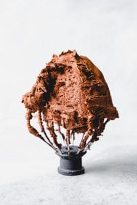 An image of a Kitchenaid whisk attachment with chocolate frosting on it.