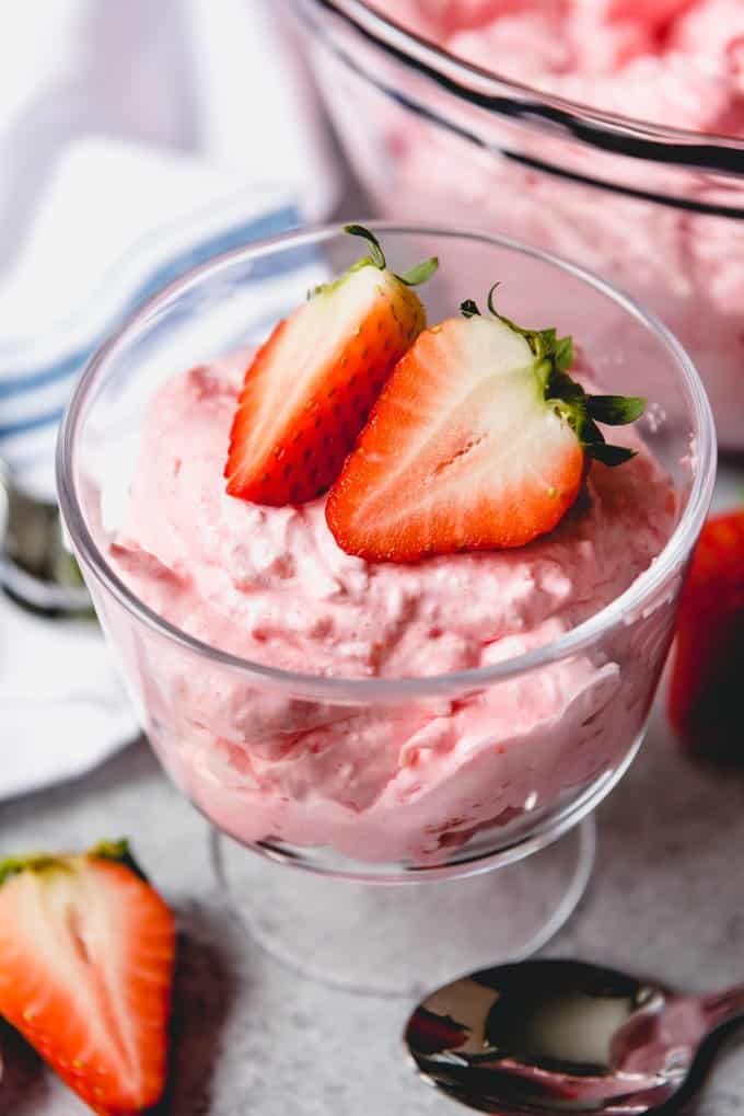 An image of a bowl of strawberry jello salad with cottage cheese, garnished with strawberry halves.