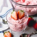 creamy strawberry cottage cheese jello in a cup and in a bowl with fresh strawberries