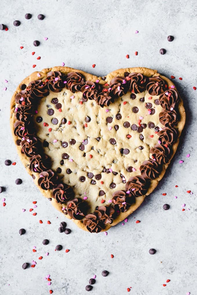 a heart shaped giant chocolate chip cookie with chocolate frosting and sprinkles