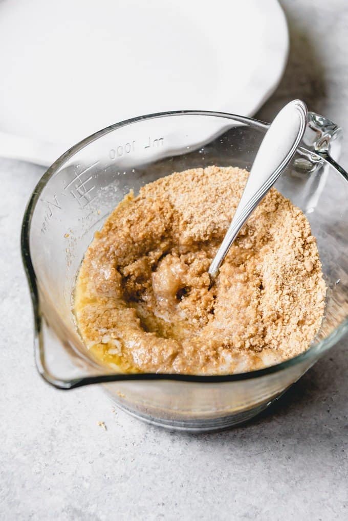 An image of graham cracker crumbs with melted butter in a bowl for making a graham cracker crust for cheesecakes or pies.
