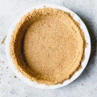 An image of a homemade graham cracker crust in a white pie plate.