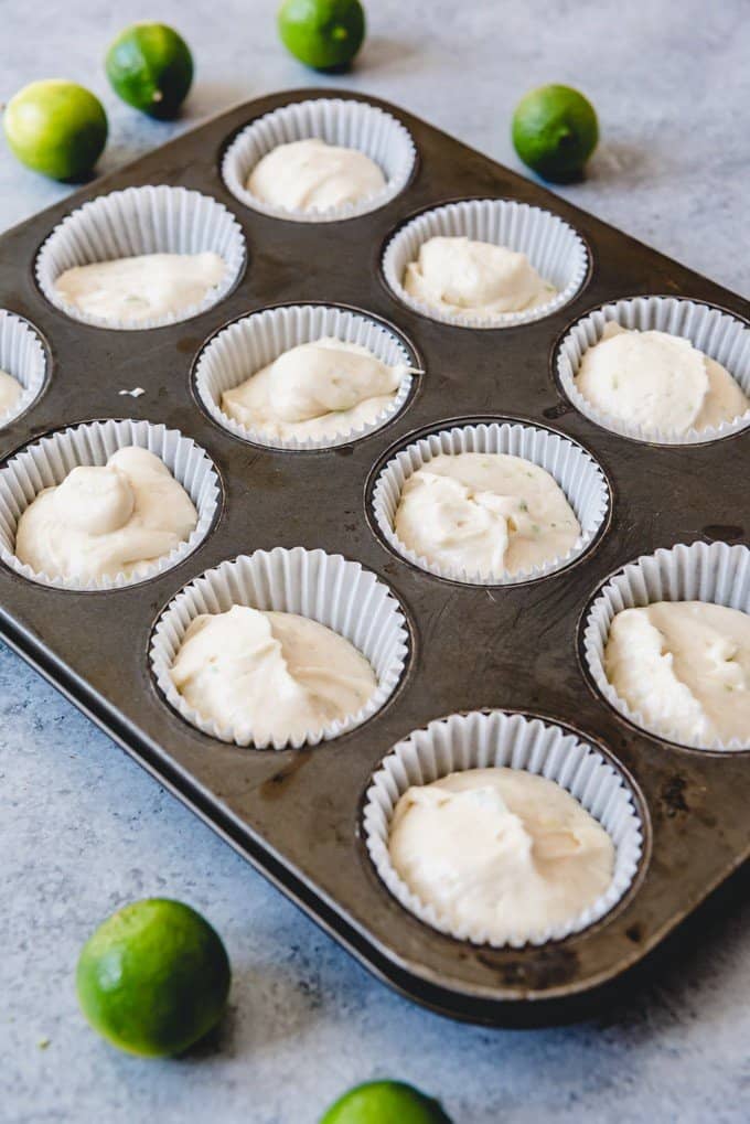 An image of cupcake liners in a muffin tin filled with key lime cupcake batter.
