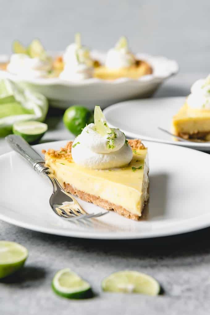 An image of a sliced key lime pie with fresh key limes surrounding it.