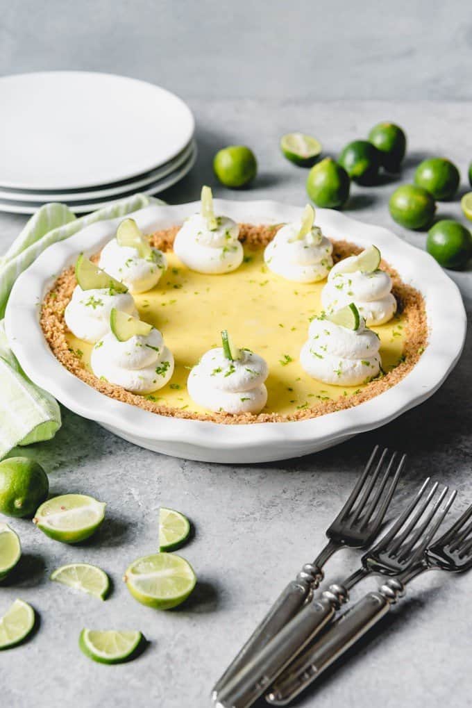 An image of a classic key lime pie topped with whipped cream swirls.