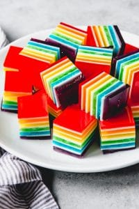 layered rainbow jello cubes on a white plate