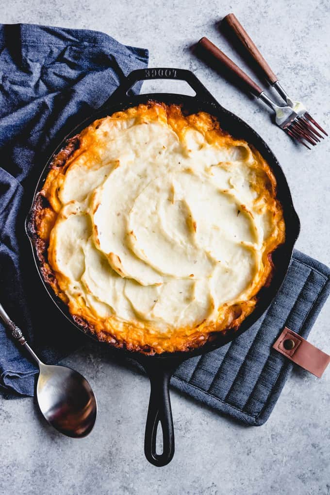 An image of shepherd's pie made in a cast iron skillet with creamy mashed potatoes on top.