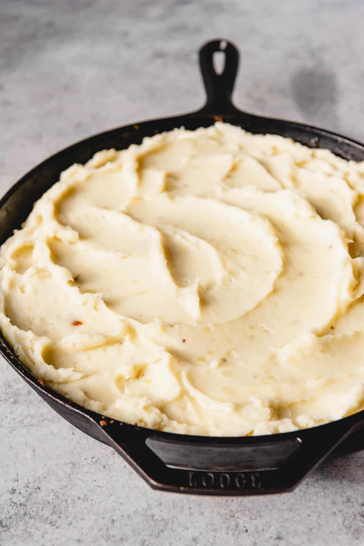 Adding a layer of mashed potatoes on the top of a shepherd's pie.