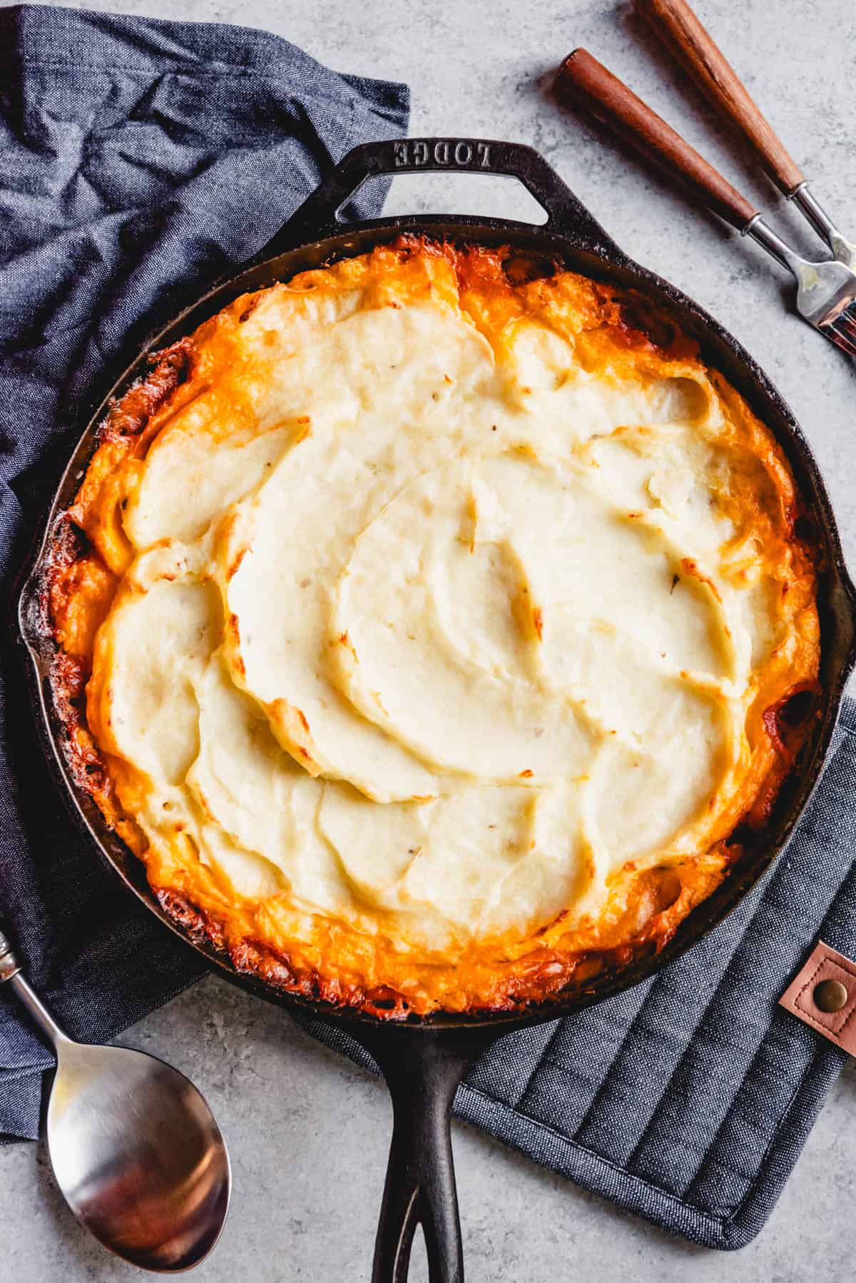 An image of shepherd's pie made in a cast iron skillet with creamy mashed potatoes on top.