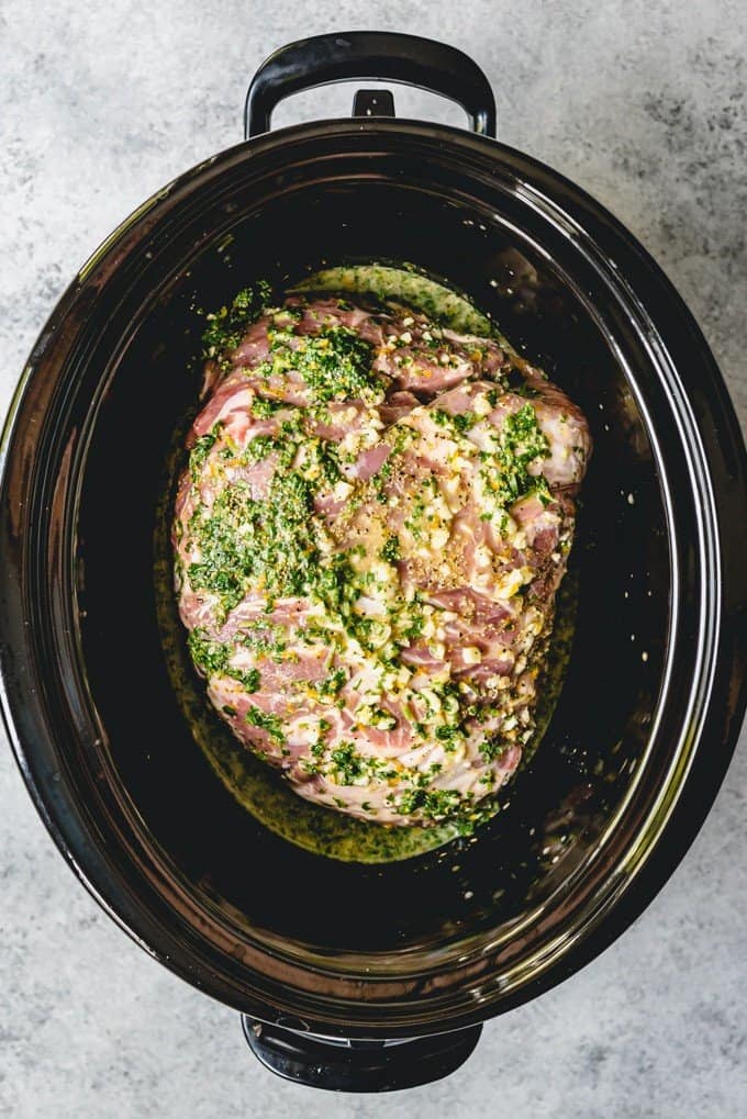 An image of a crock pot filled with a pork butt covered in Cuban mojo sauce for slow cooker Cuban mojo pork.
