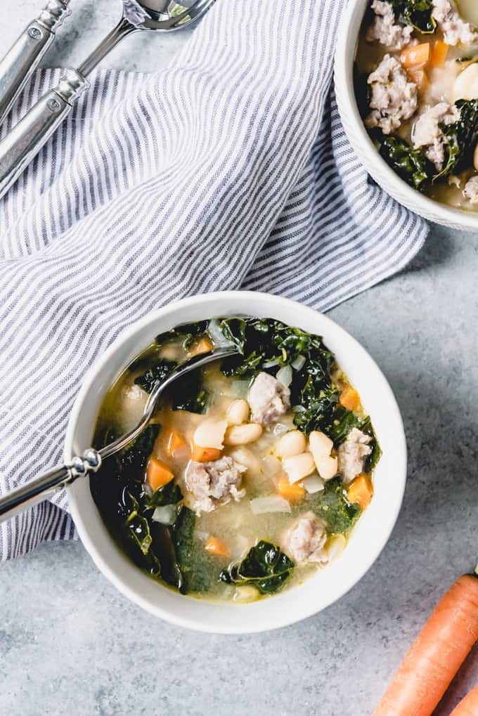 An image of a Slow Cooker Bean Soup made in the style of Tuscany with Italian sausage, kale, carrots, onions, and cannellini beans.