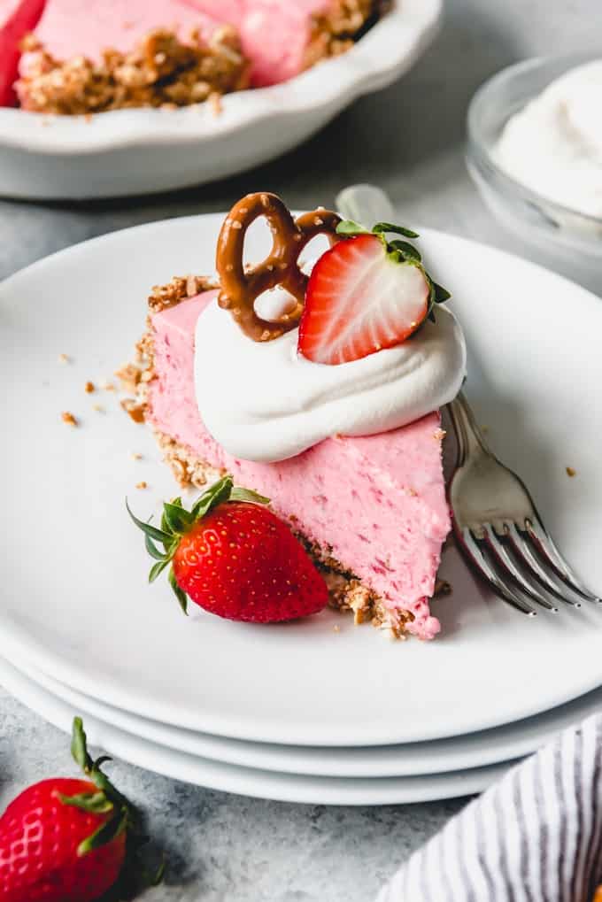 Strawberry Pretzel Icebox Pieslice on a stack of white plates with garnishes and a fork