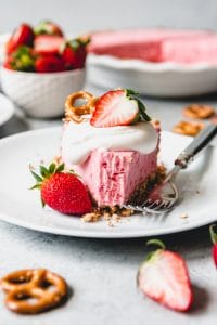 a white plate with a slice of Strawberry Pretzel Icebox Pie and a bitemissing