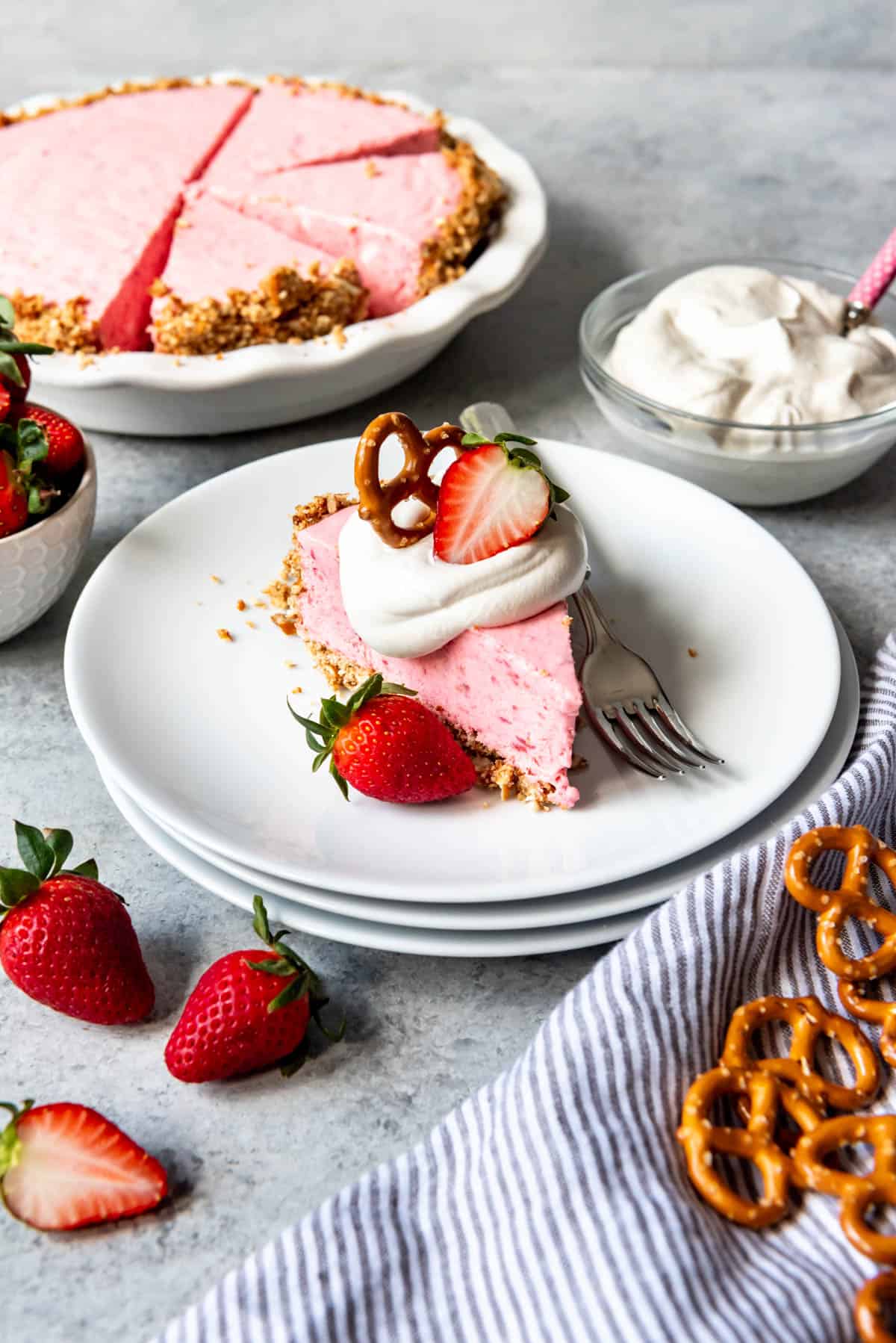 A slice of strawberry pretzel icebox pie on a stack of white plates.