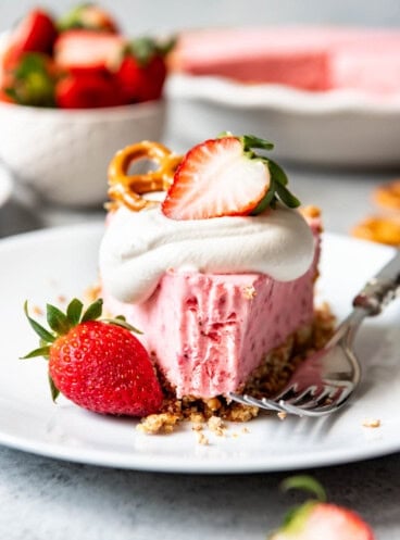 a close view of a white plate with a slice of Strawberry Pretzel Icebox Pie and a bite missing from the front