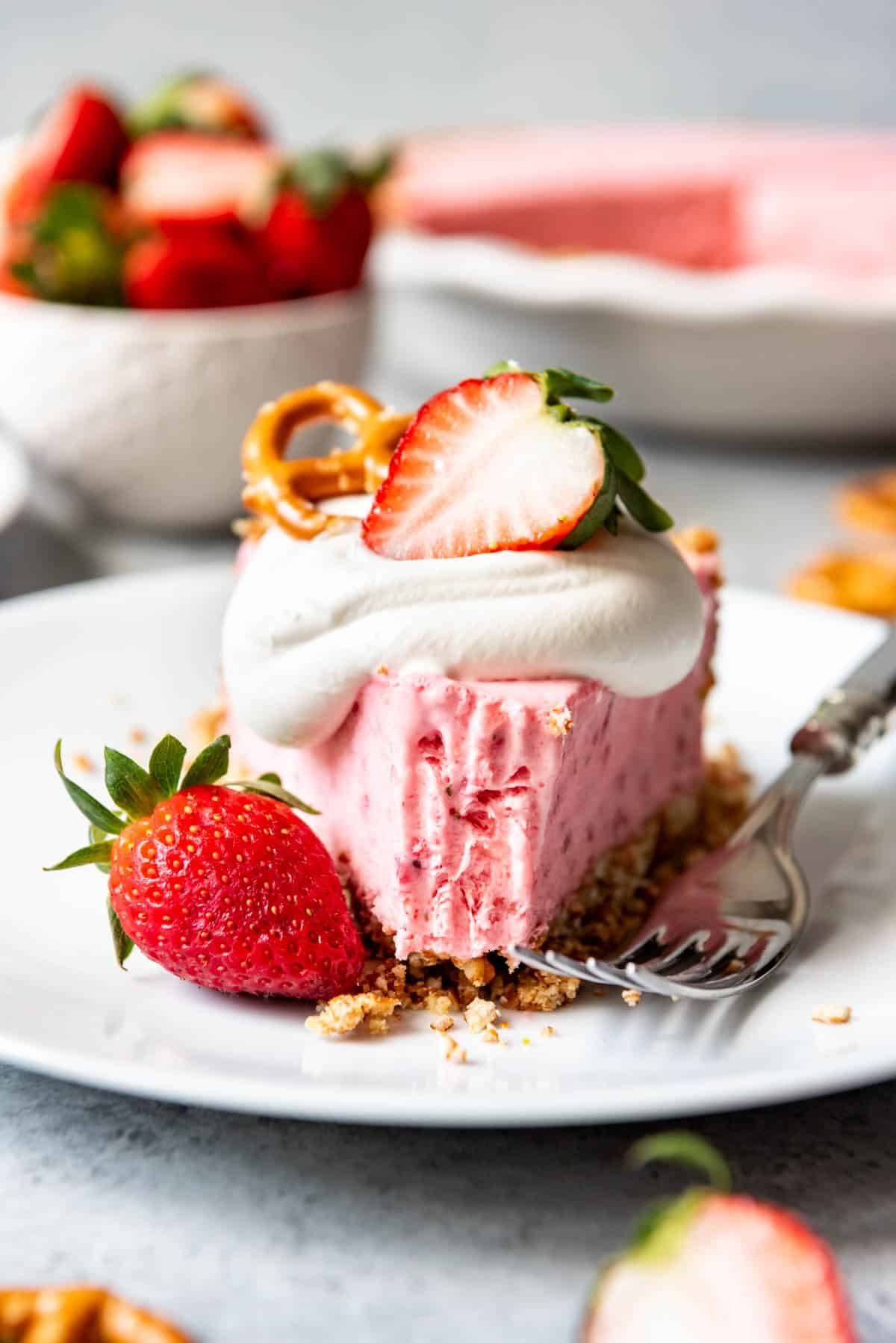 a close view of a white plate with a slice of Strawberry Pretzel Icebox Pie and a bite missing from the front