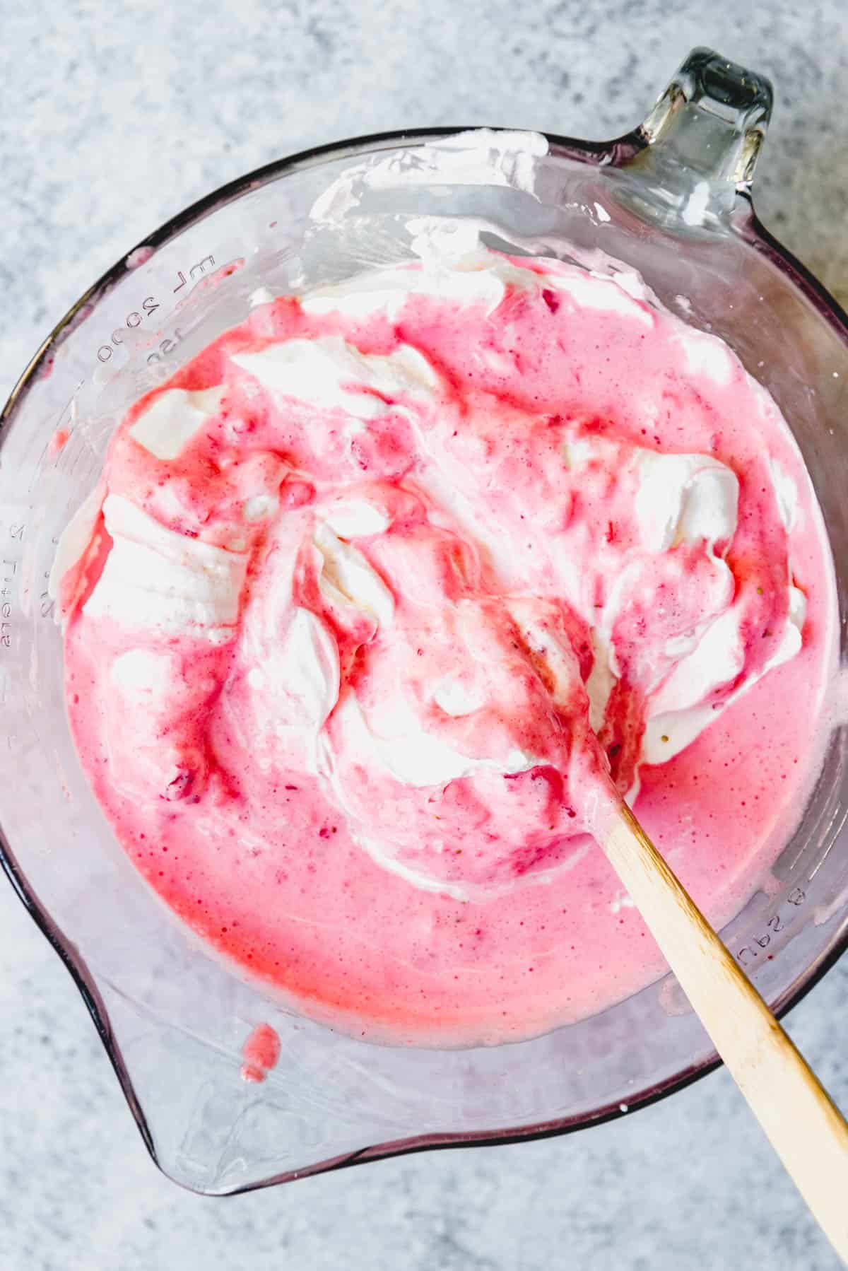 Folding whipped cream into strawberry filling.