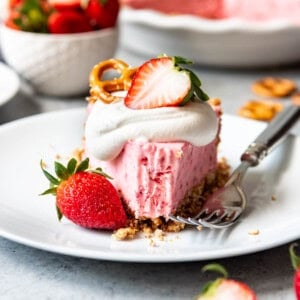 a close view of a white plate with a slice of Strawberry Pretzel Icebox Pie and a bite missing from the front