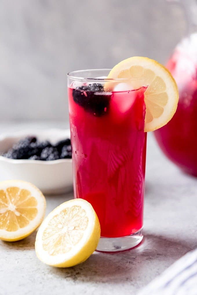 An image of a glass of fresh squeezed blackberry lemonade garnished with a blackberry and a lemon slice.