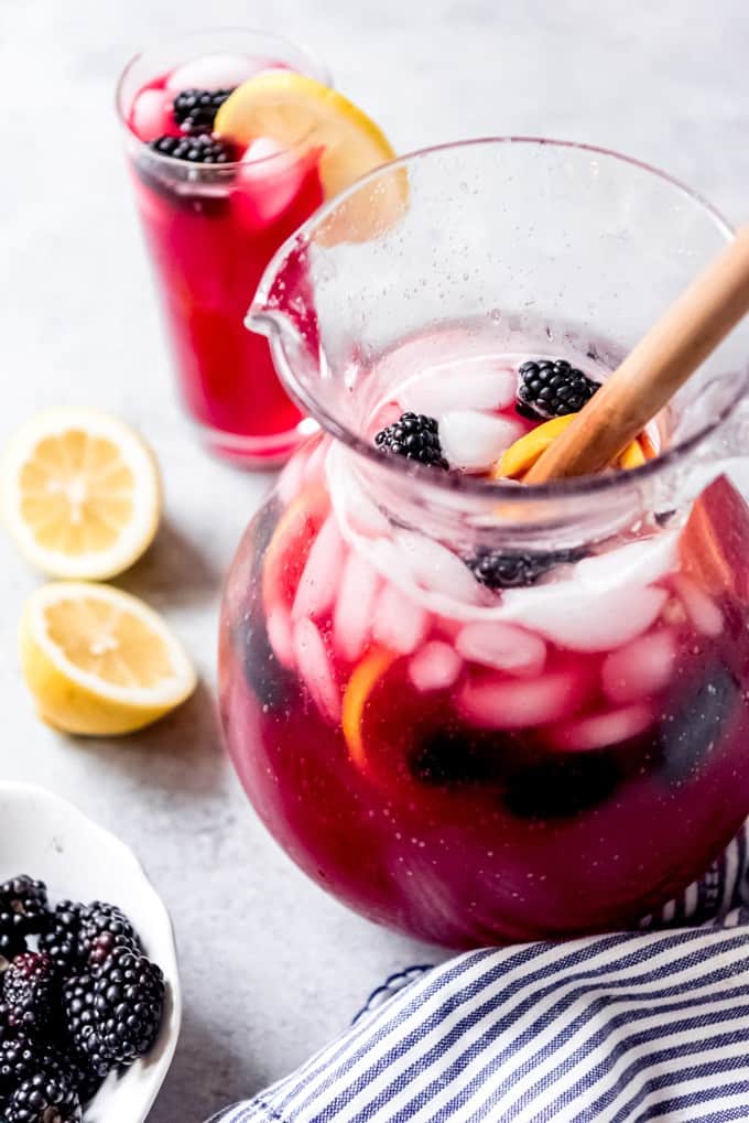 An image of a glass pitcher full of homemade blackberry lemonade with ice, blackberries, and lemon slices.