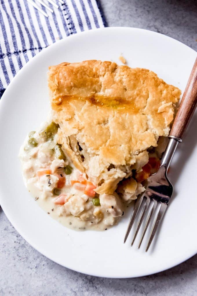 An image of a slice of homemade chicken pot pie with carrots, celery, onions, chicken under a flaky, buttery crust.