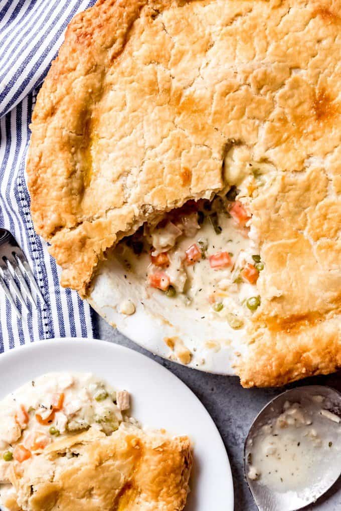 An image of the best chicken pot pie with a big piece taken out and served on a plate next to it.