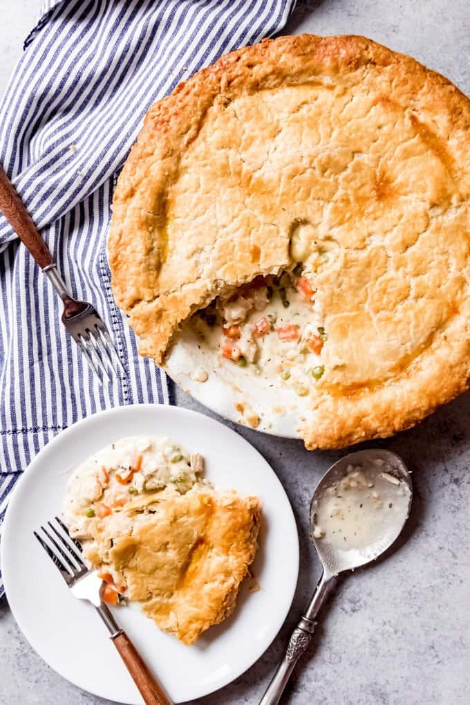 An image of the best chicken pot pie with a big piece taken out and served on a plate next to it.