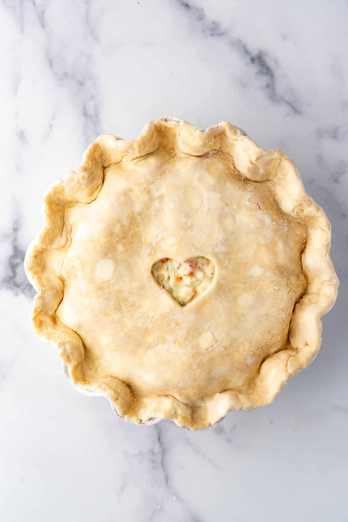 Adding an unbaked pie crust over pot pie filling.