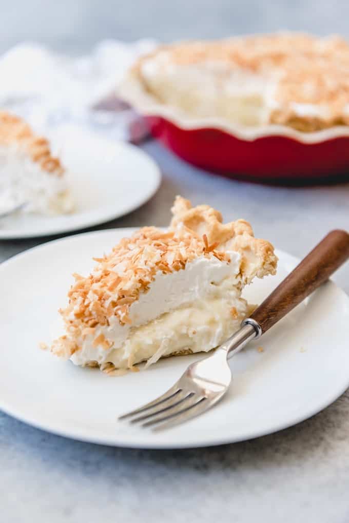 coconut cream pie slices on plates with a red pie plate in the background