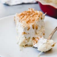 A slice of coconut cream pie on a plate with a bite taken out of it