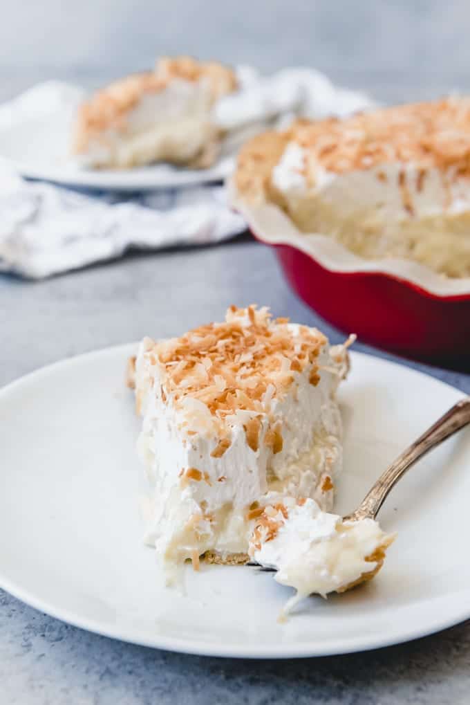 A slice of homemade coconut cream pie with a bite taken out of it.