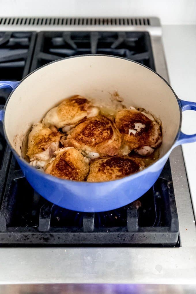 An image of chicken pieces being seared in a dutch oven on the stovetop.