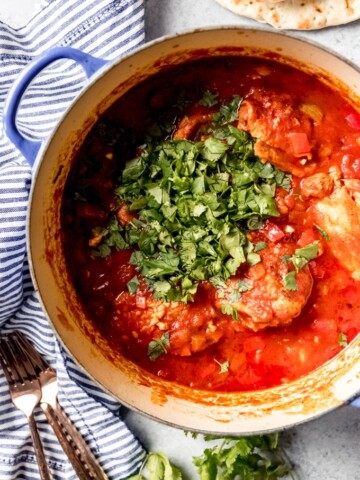 An aerial view of Georgian Chicken Stew with Tomatoes and Herbs in a dutch oven.